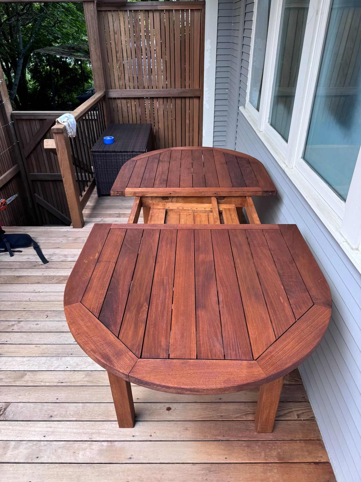 A wooden table is sitting on a wooden deck next to a window.