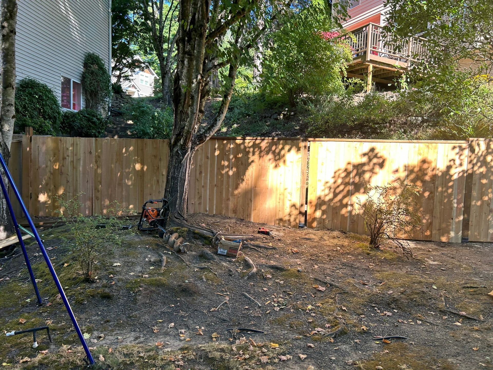 A wooden fence is being built in the backyard of a house.