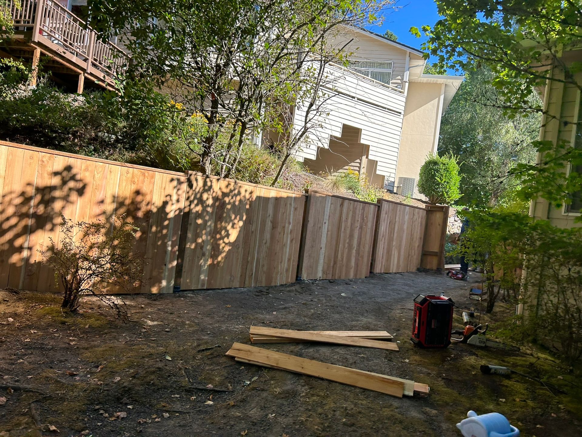 A wooden fence is being built in the backyard of a house.