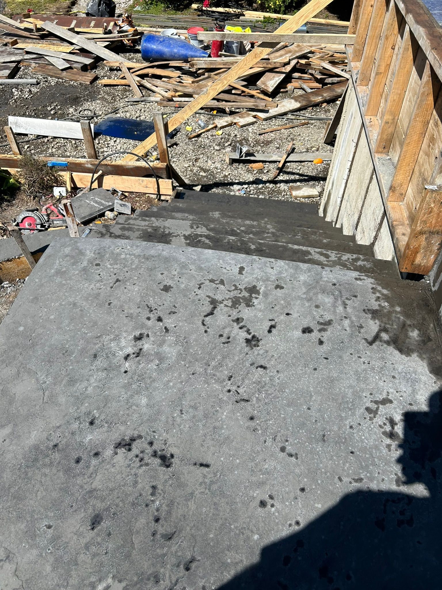 A pile of concrete is sitting on the ground next to a pile of wood.