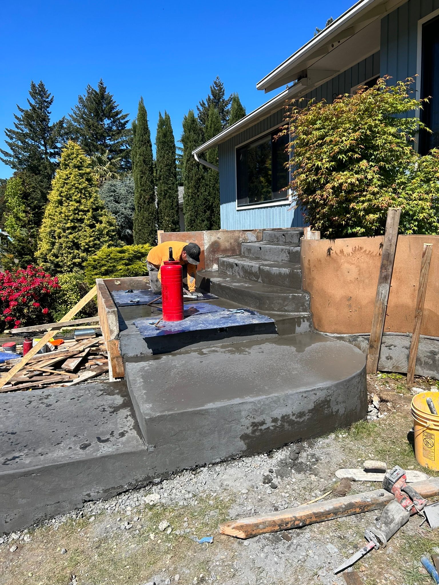 A man is working on a concrete walkway in front of a house.