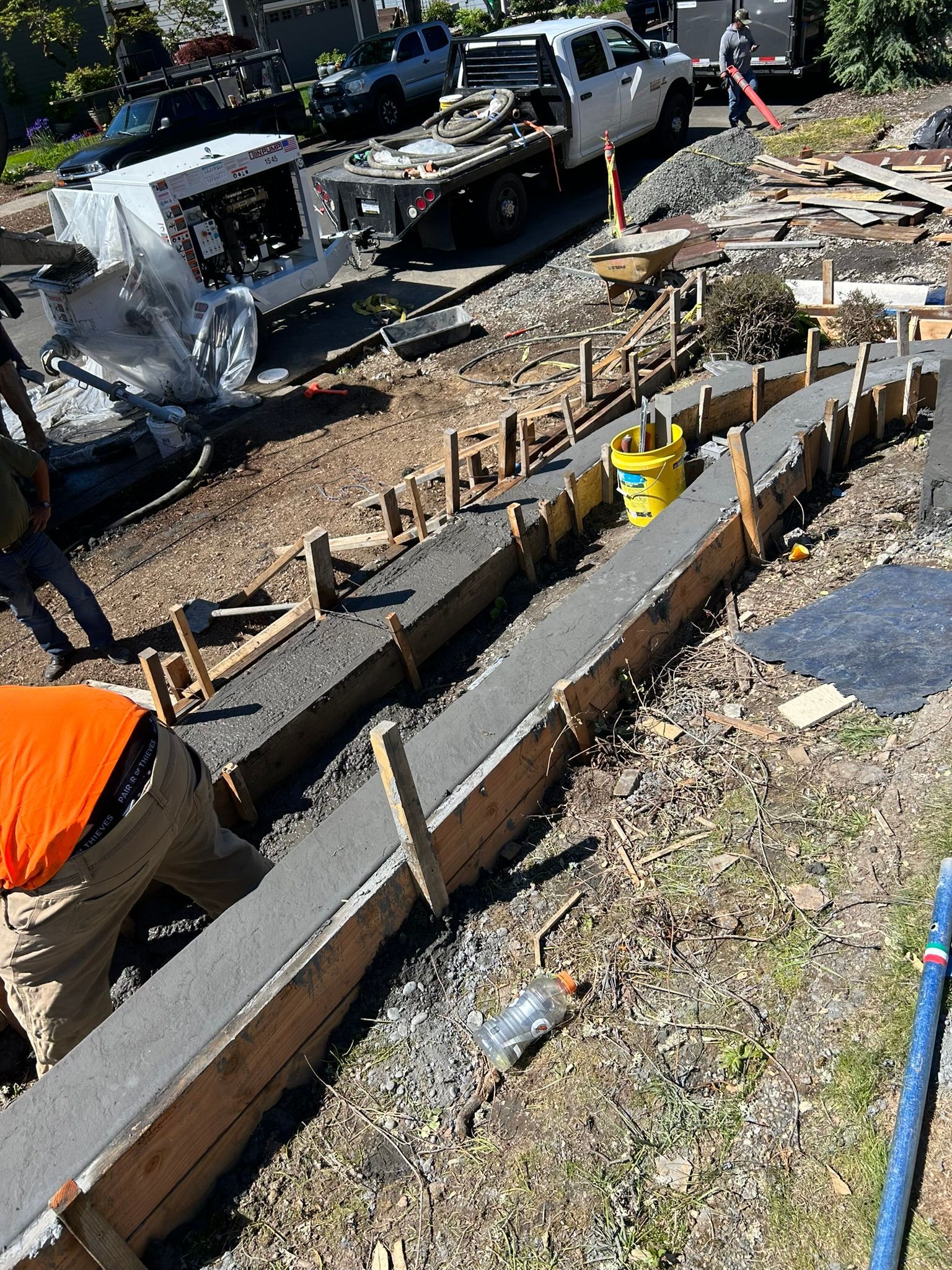 A concrete curb is being built in a yard with a truck in the background.