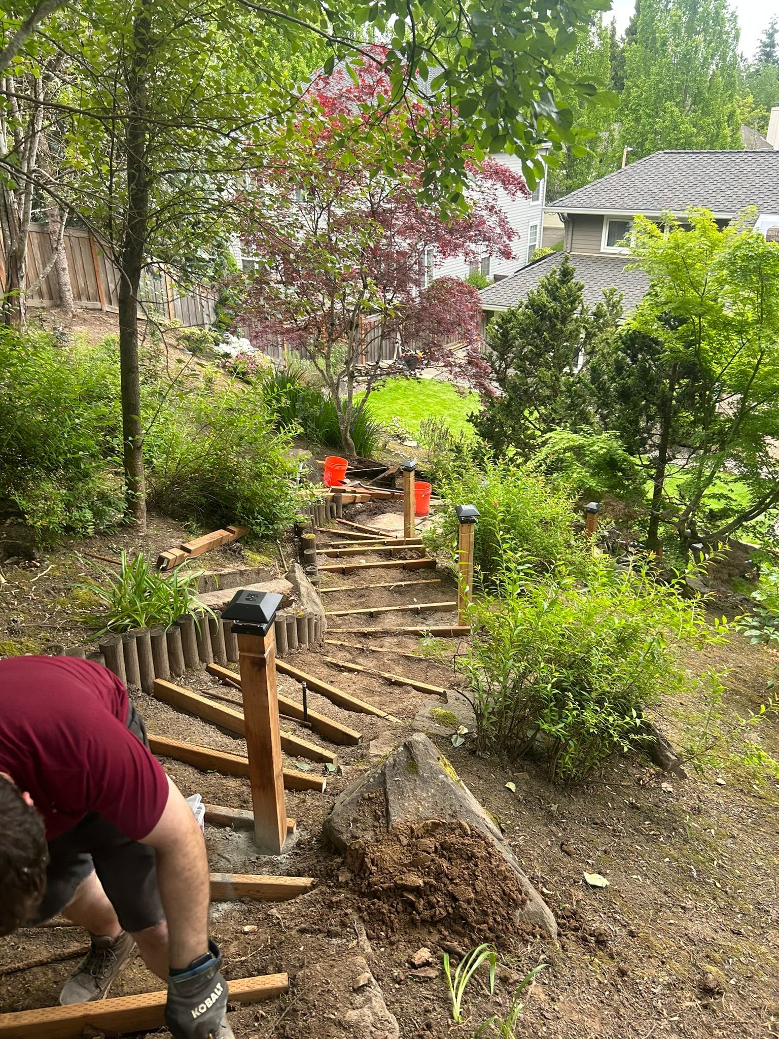 A man is working on a wooden staircase in a garden.