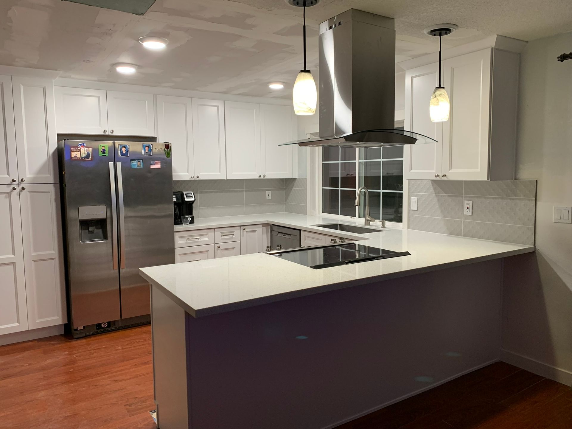 A kitchen with white cabinets , stainless steel appliances , a refrigerator and a stove.