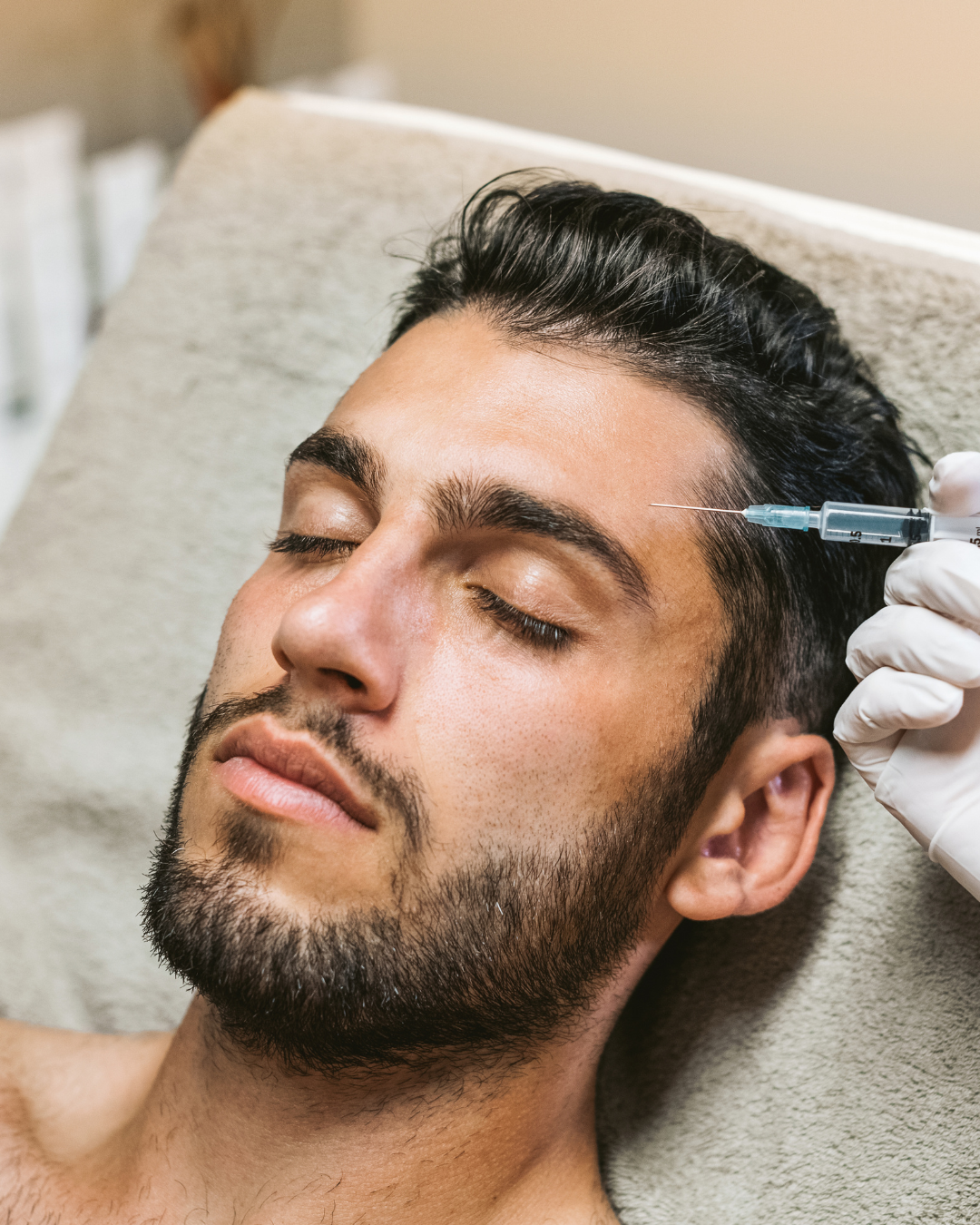 Man receiving a facial injection near his temple in a clinical setting