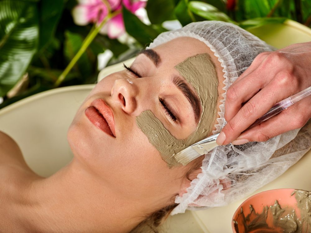 Woman Receiving a Facial Mask Treatment While Lying on A Spa Bed — Hope Laser and Beauty Clinic In Taree, NSW