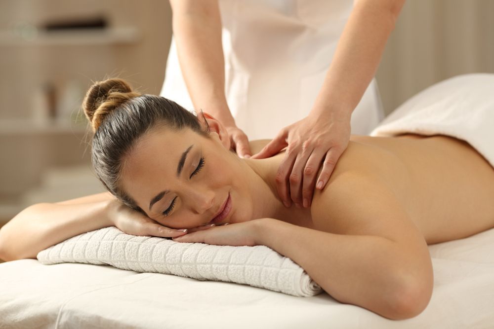 Person Receiving a Shoulder Massage on A Bed, with Eyes Closed and A Relaxed Expression — Hope Laser and Beauty Clinic In Forster, NSW