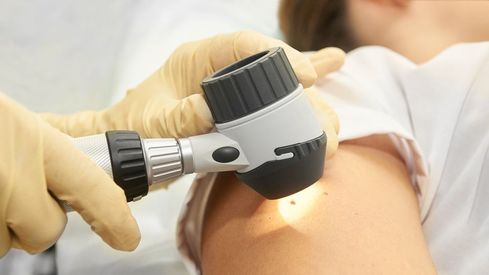 Dermatologist Examining a Patient's Arm With a Dermatoscope — Hope Laser and Beauty Clinic In Taree, NSW