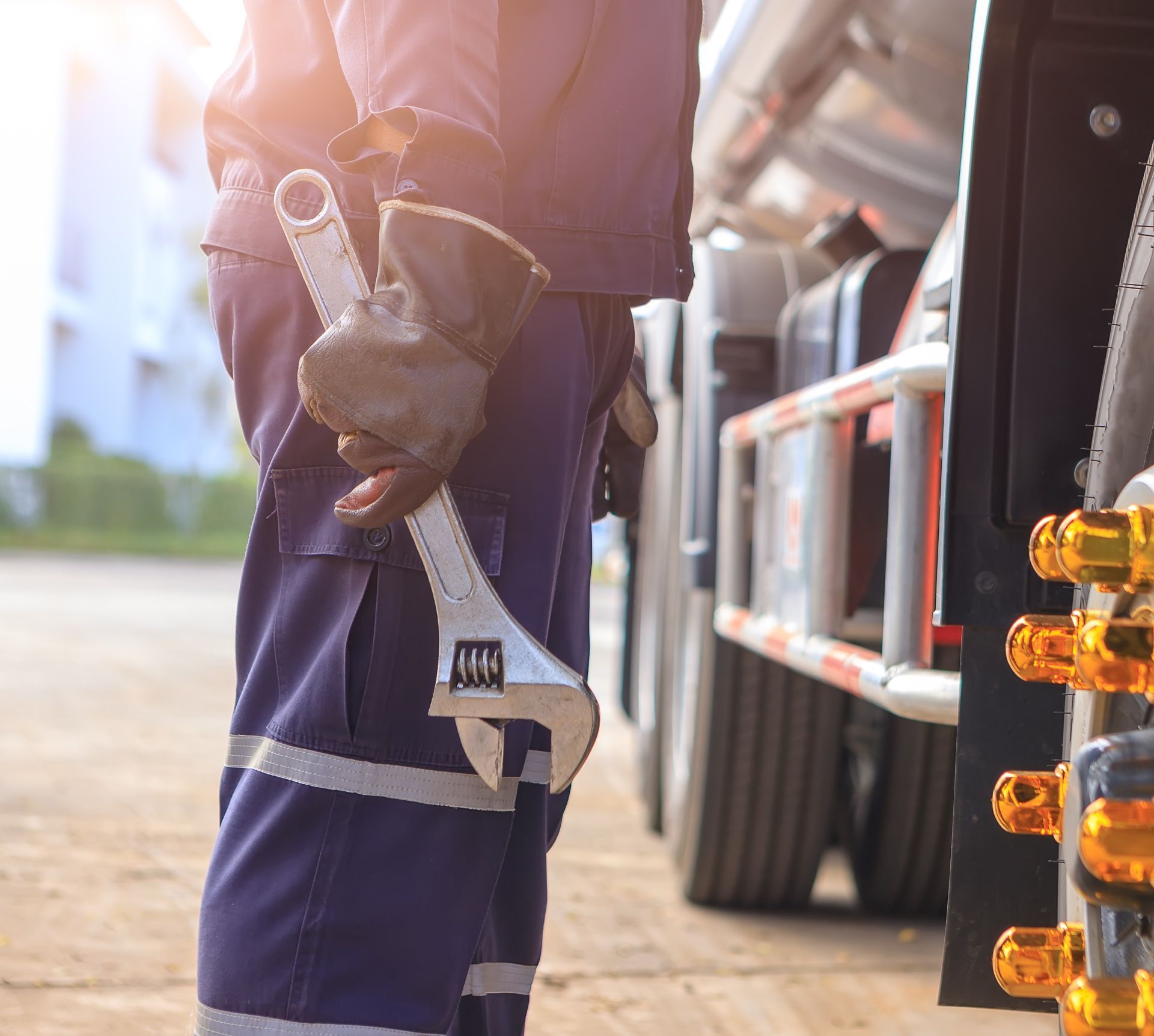 A Man Is Holding a Wrench in Front of A Truck.