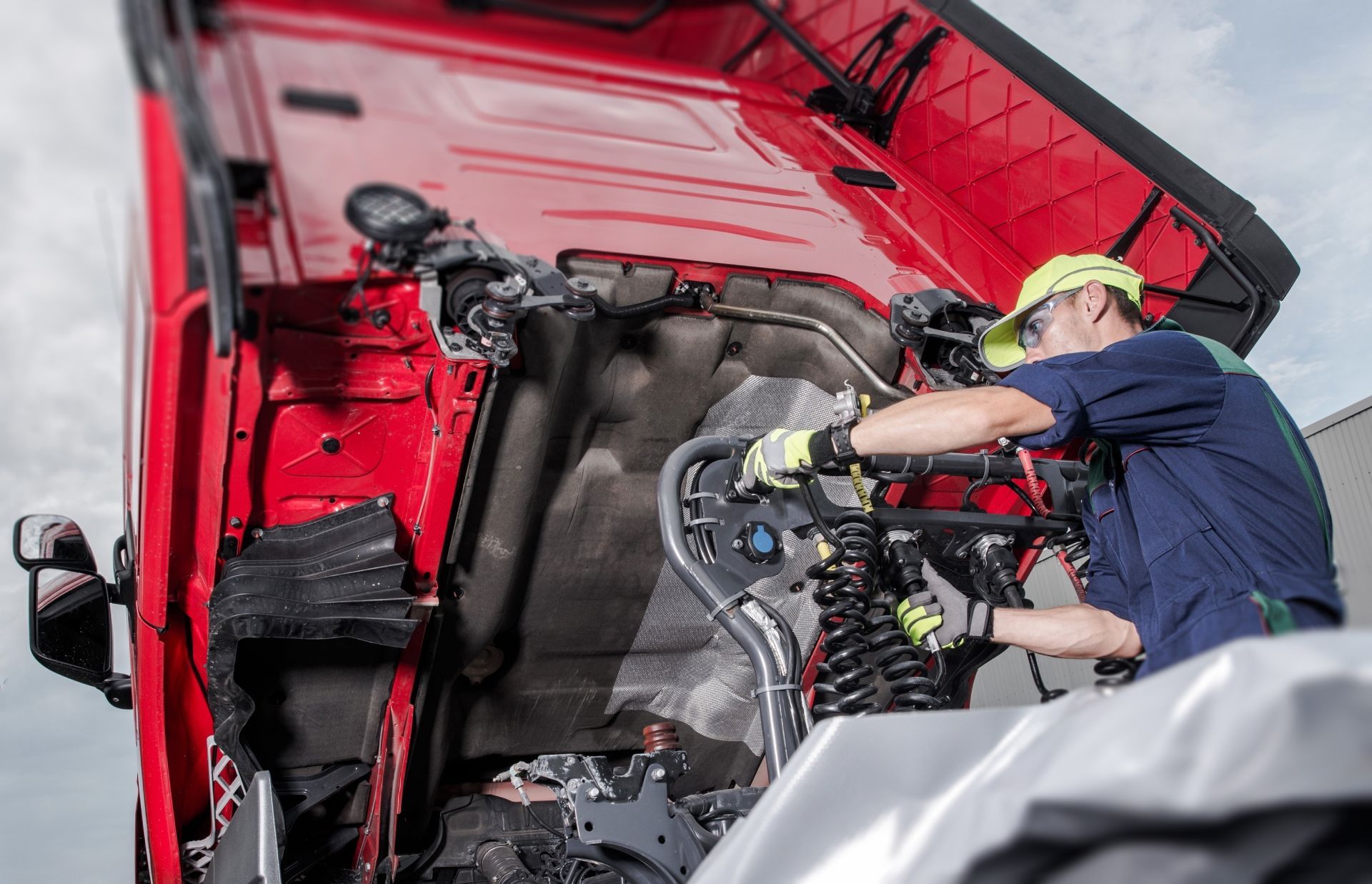 A Man Is Working on The Engine of A Red Truck.