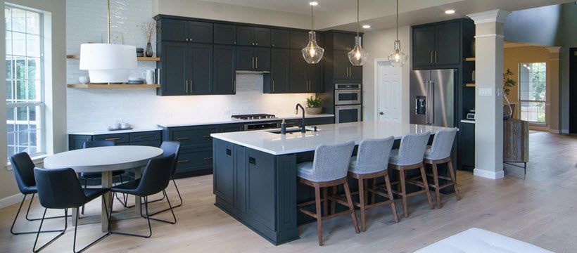 Modern kitchen with dark blue cabinets, white countertops, and an island with bar stools.