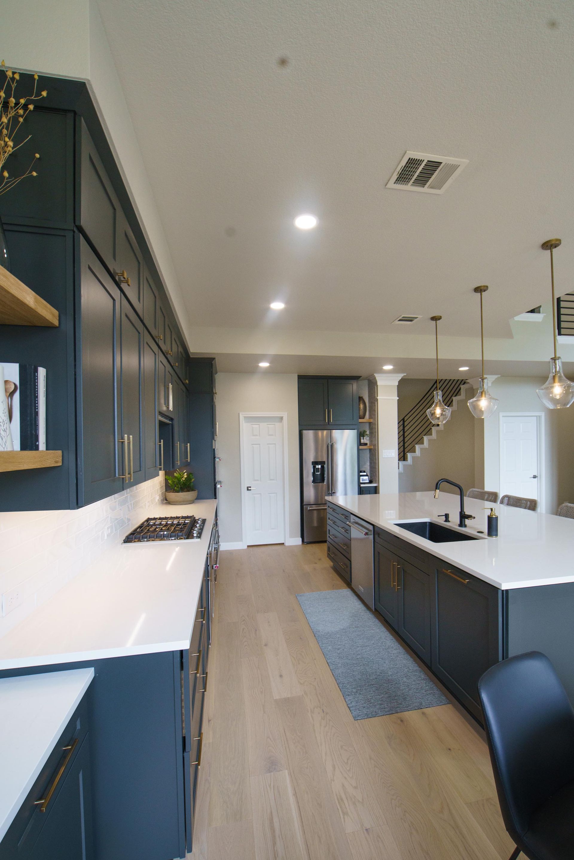 Dark blue kitchen with white countertops and light wood floors.