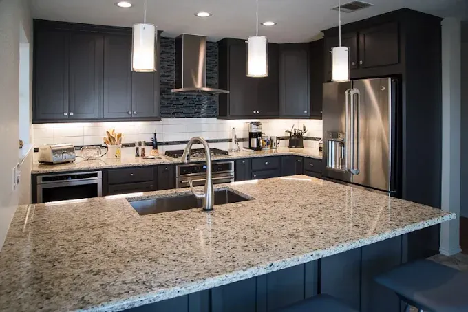 Modern kitchen with dark cabinets, stainless steel appliances, and a granite countertop island.