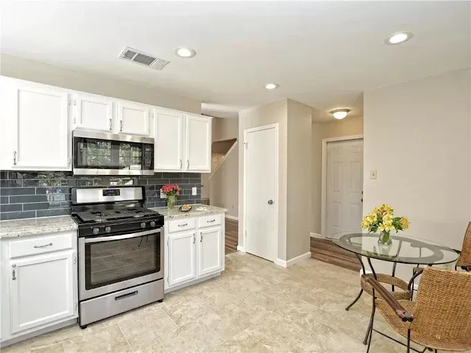 Kitchen with white cabinets, stainless steel appliances, and a small dining table.