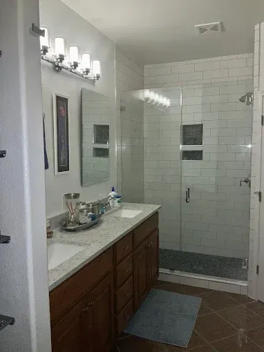 Bathroom with a double sink vanity and a tiled shower.