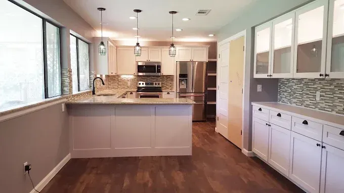 Modern kitchen with light cabinets, island, and stainless steel appliances.