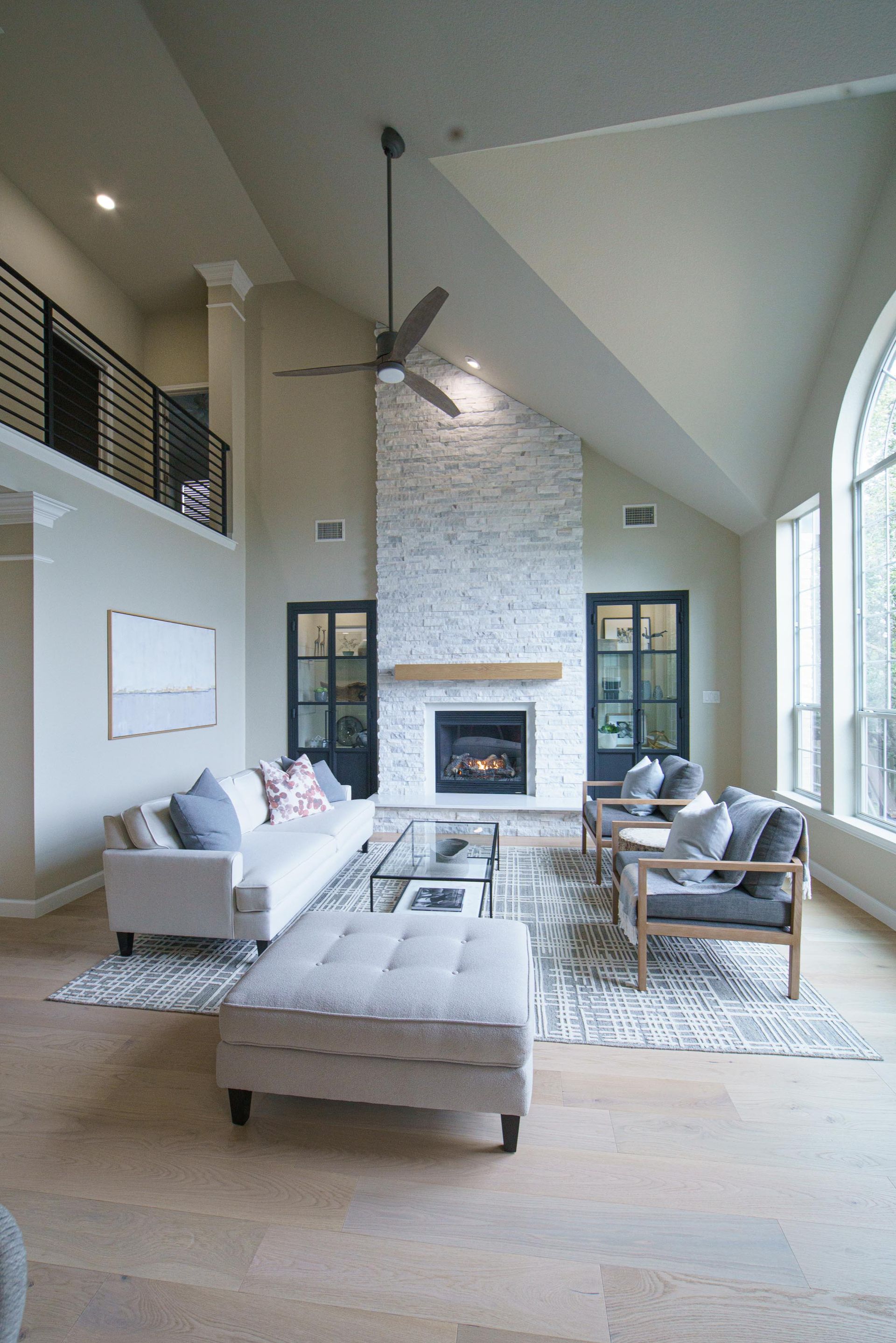Spacious living room with fireplace, high ceilings, and neutral color scheme.