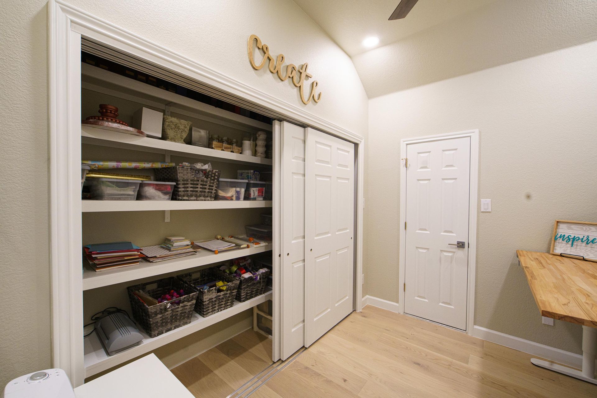 Craft room with closet, white sliding doors, open shelves, and wooden 