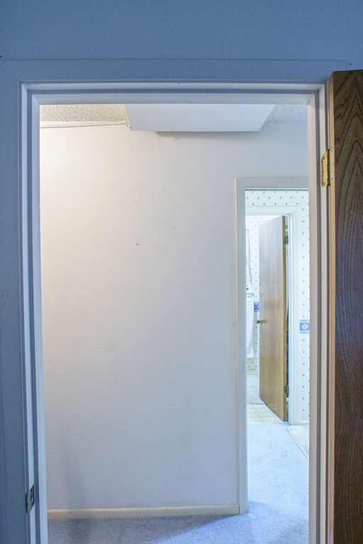 View through doorways: white wall, another doorway, and a bathroom.