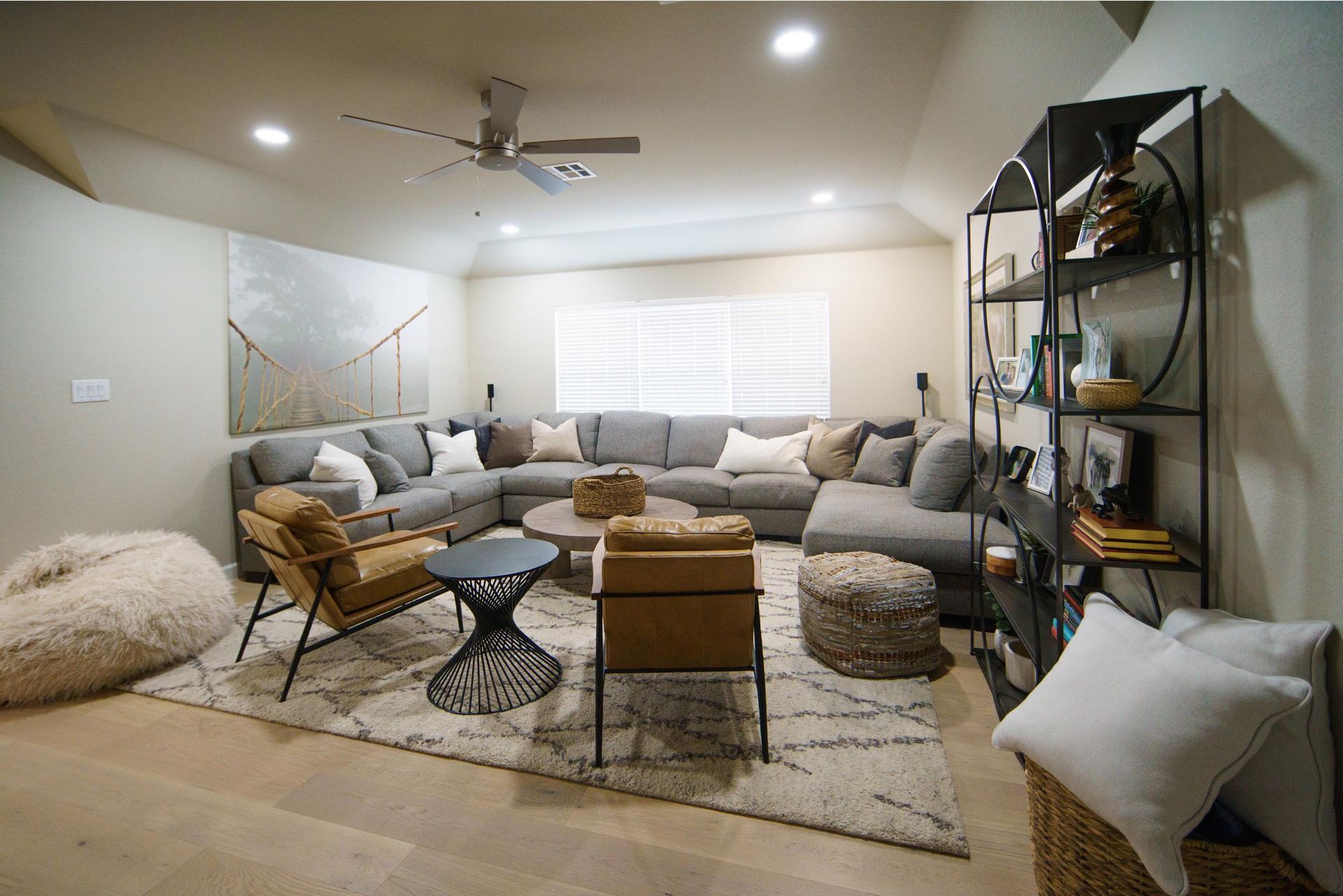 Cozy living room with large gray sectional, rug, and black metal shelving filled with decor.