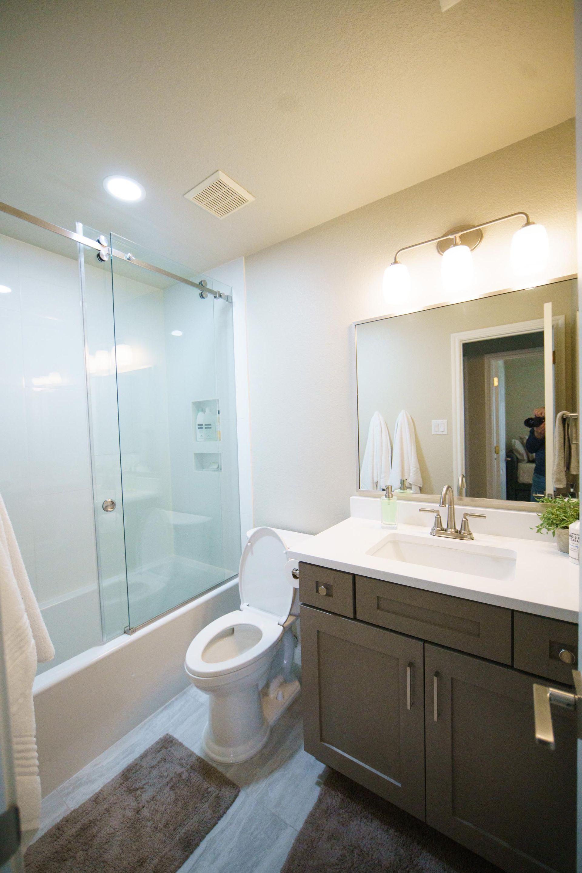 Bathroom with a shower, toilet, vanity, and a light-colored floor.