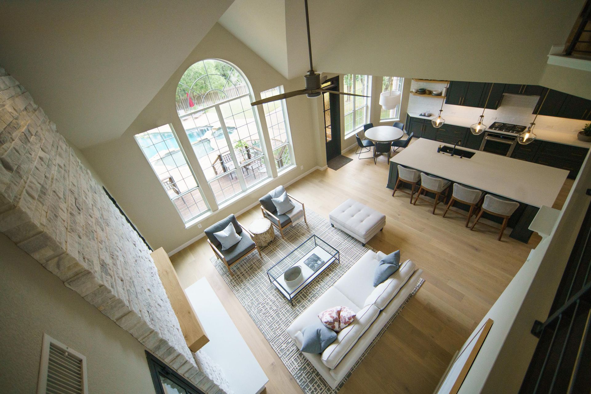 High-angle shot of a modern living area with a tall ceiling, windows, and light wood floors.