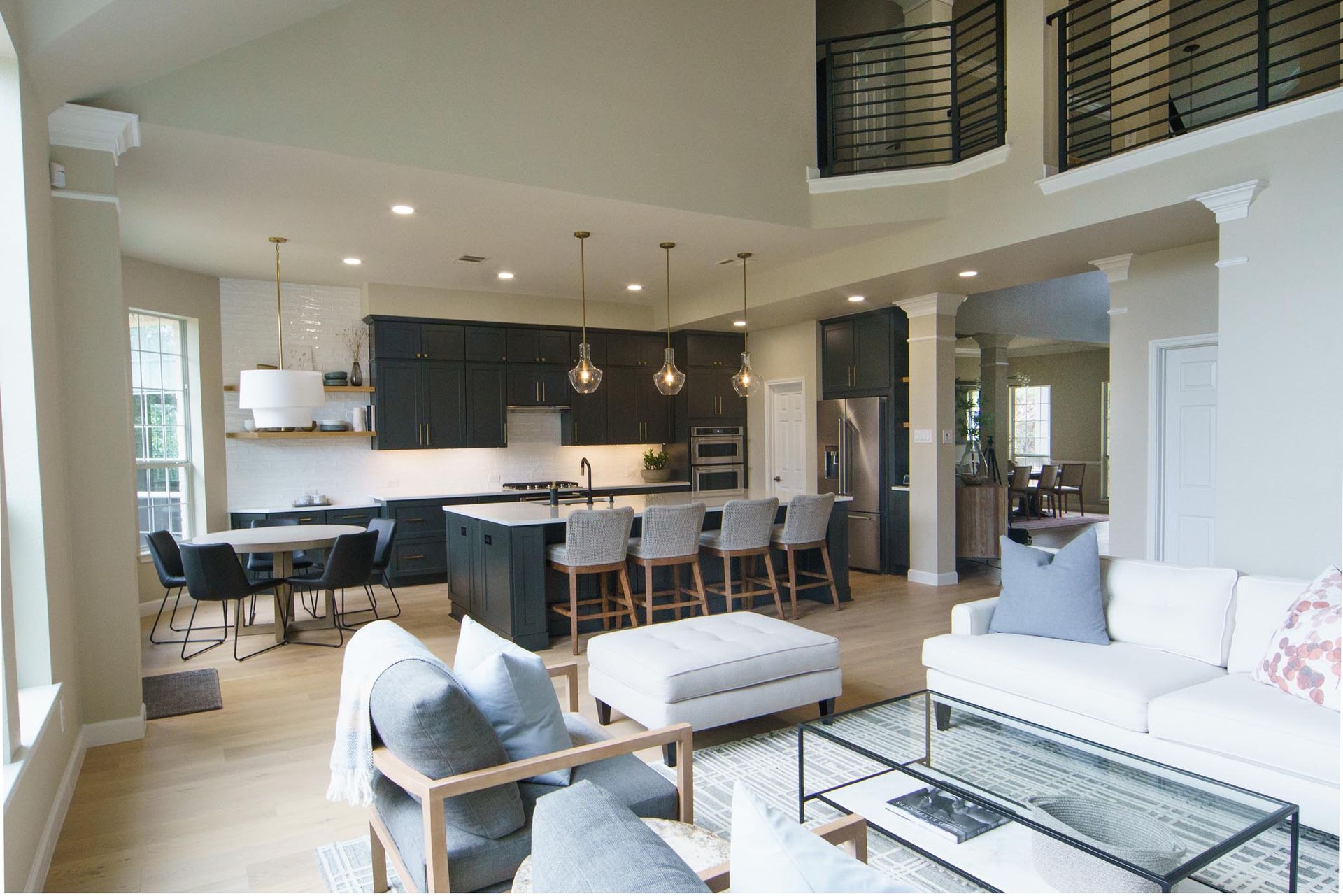 Spacious open-concept kitchen and living area with dark cabinets, island seating, and a white sofa.