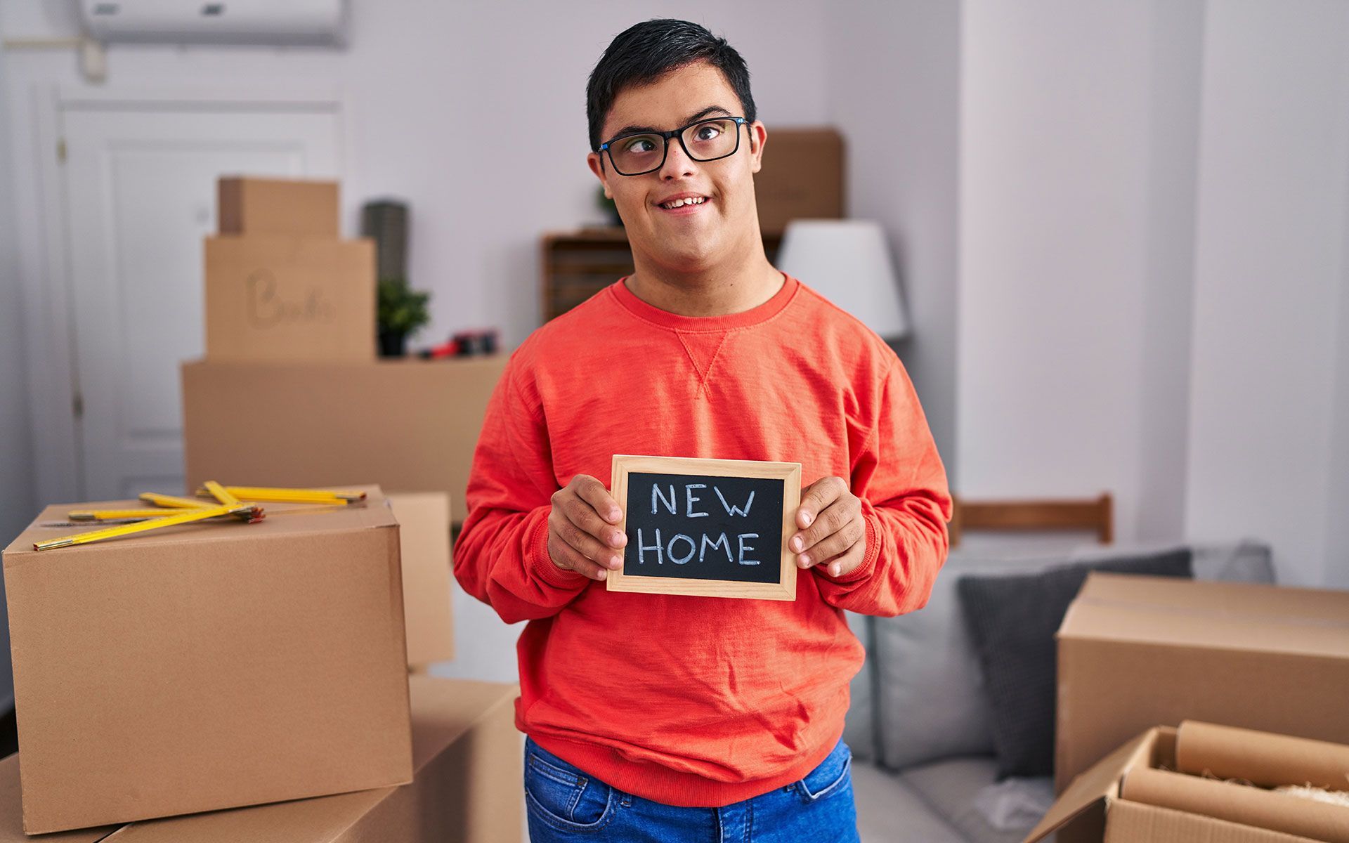 A young man is holding a sign that says `` new home ''.