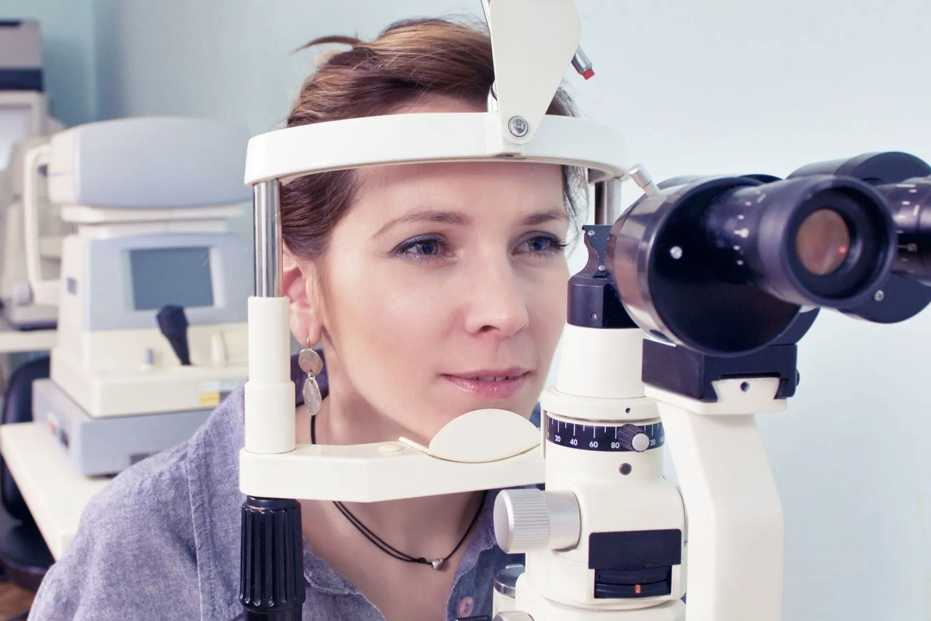 Donna sottoposta a visita oculistica, che osserva uno strumento oftalmico in un ambiente clinico.