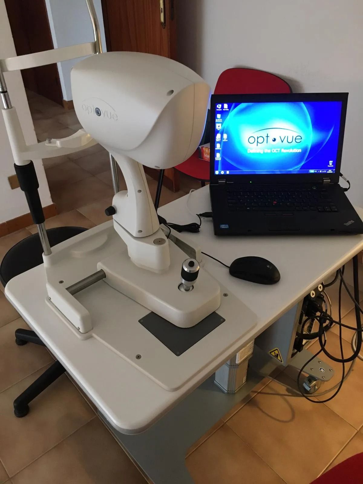 Un apparecchio oftalmico e un computer portatile su un tavolo bianco. 