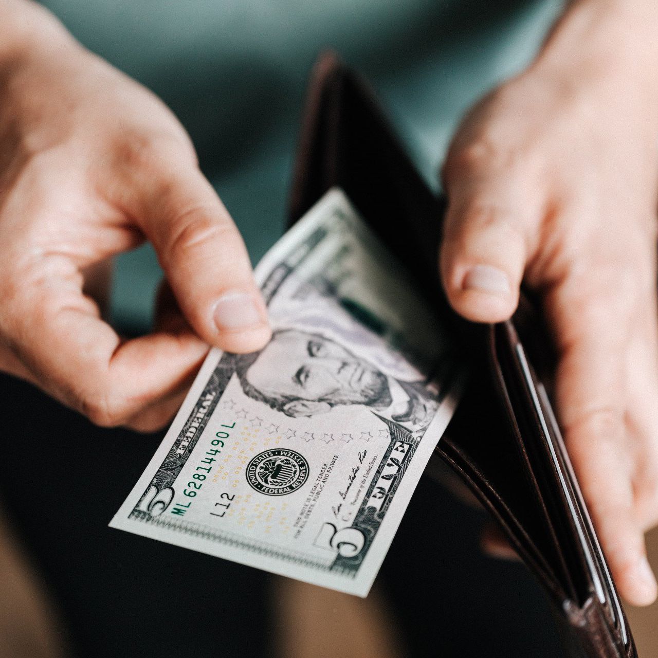 a person takes a five dollar bill out of their wallet