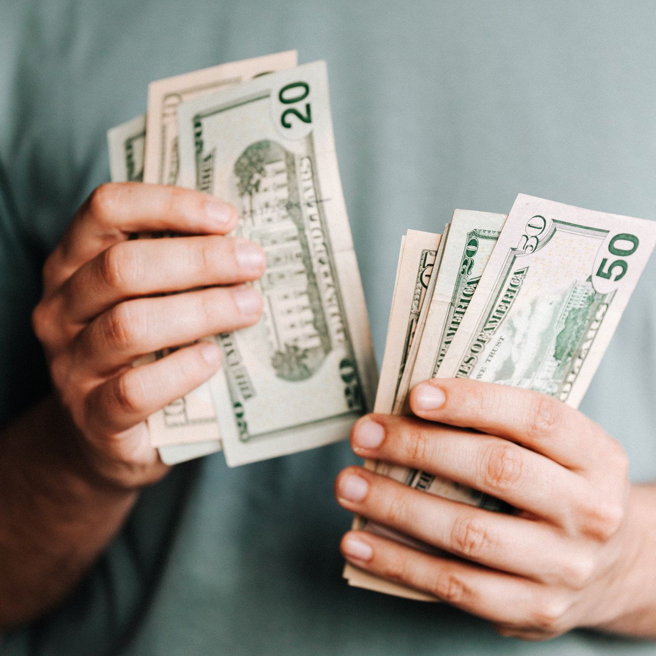 a person holding a stack of 20 and 50 dollar bills