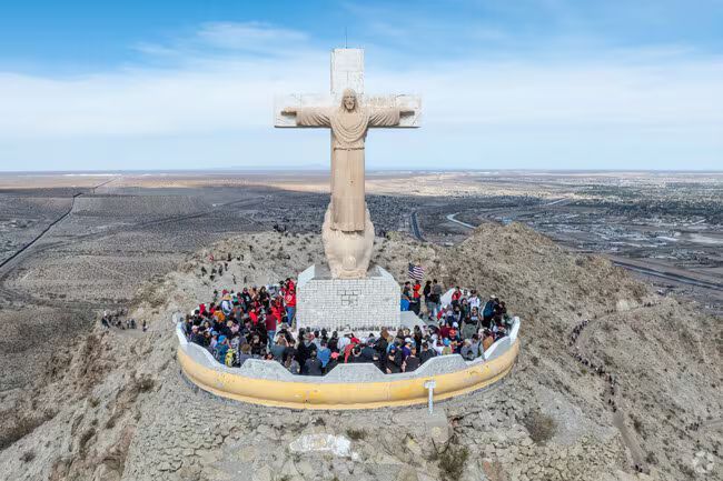 Aerial view of the Christ of the Noas statue atop a rocky hill in Torreón, Mexico, surrounded by a crowd of visitors.