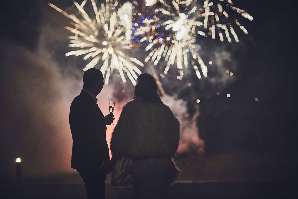 a group of people are standing in front of a fireworks display .