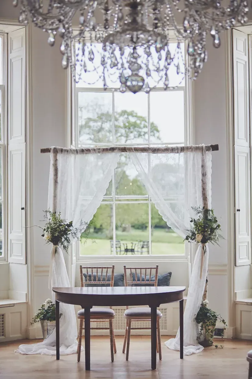 a room with a table and chairs in front of a window .