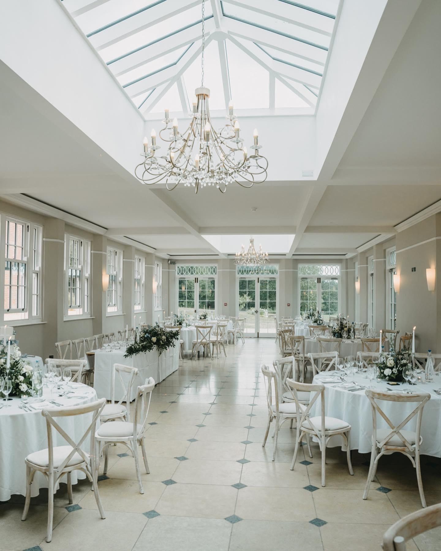 a large room with tables and chairs and a chandelier hanging from the ceiling
