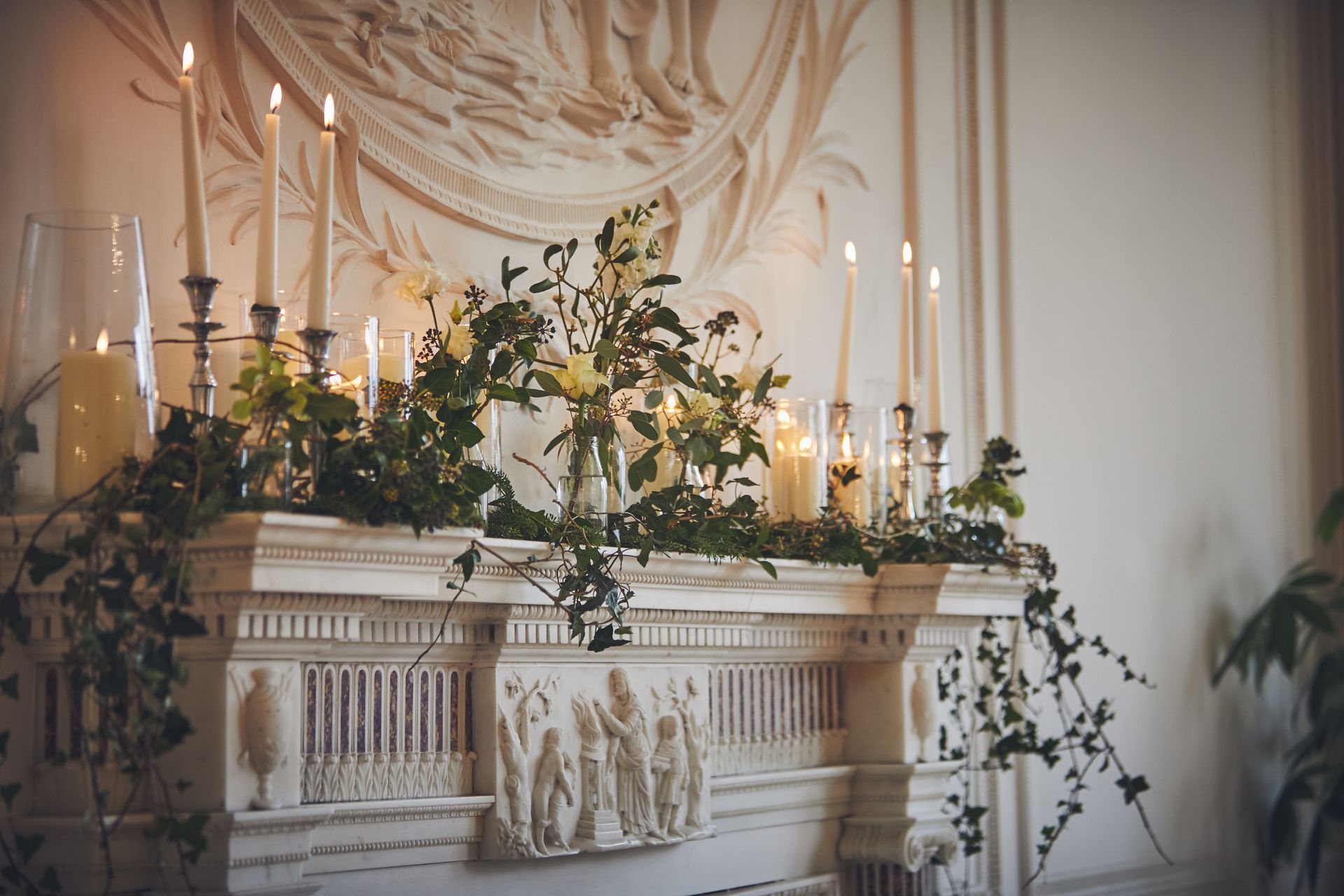 Mantlepiece decorated with candles and ivy.