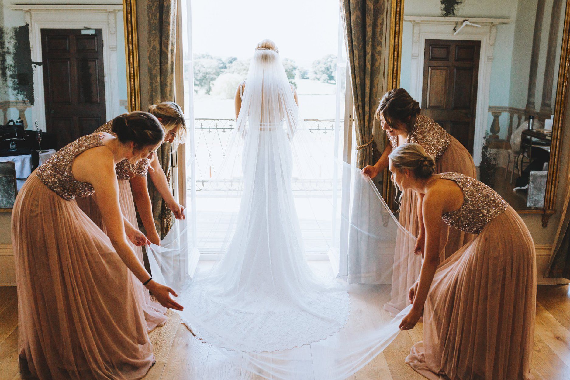 a bride and her bridesmaids are putting on their wedding dress .