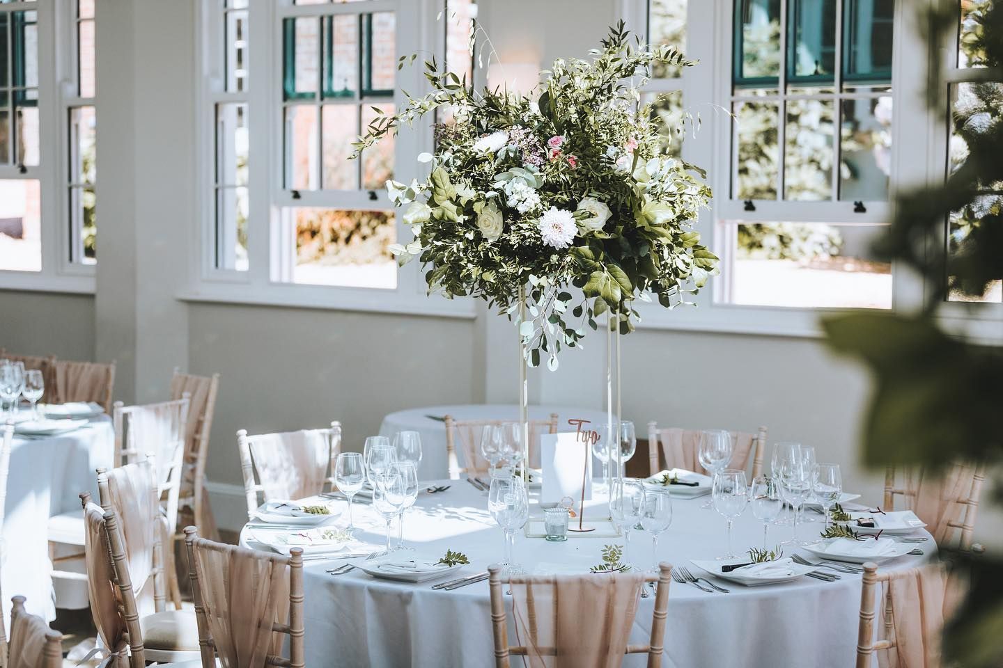 a table set for a wedding reception with a vase of flowers on it .