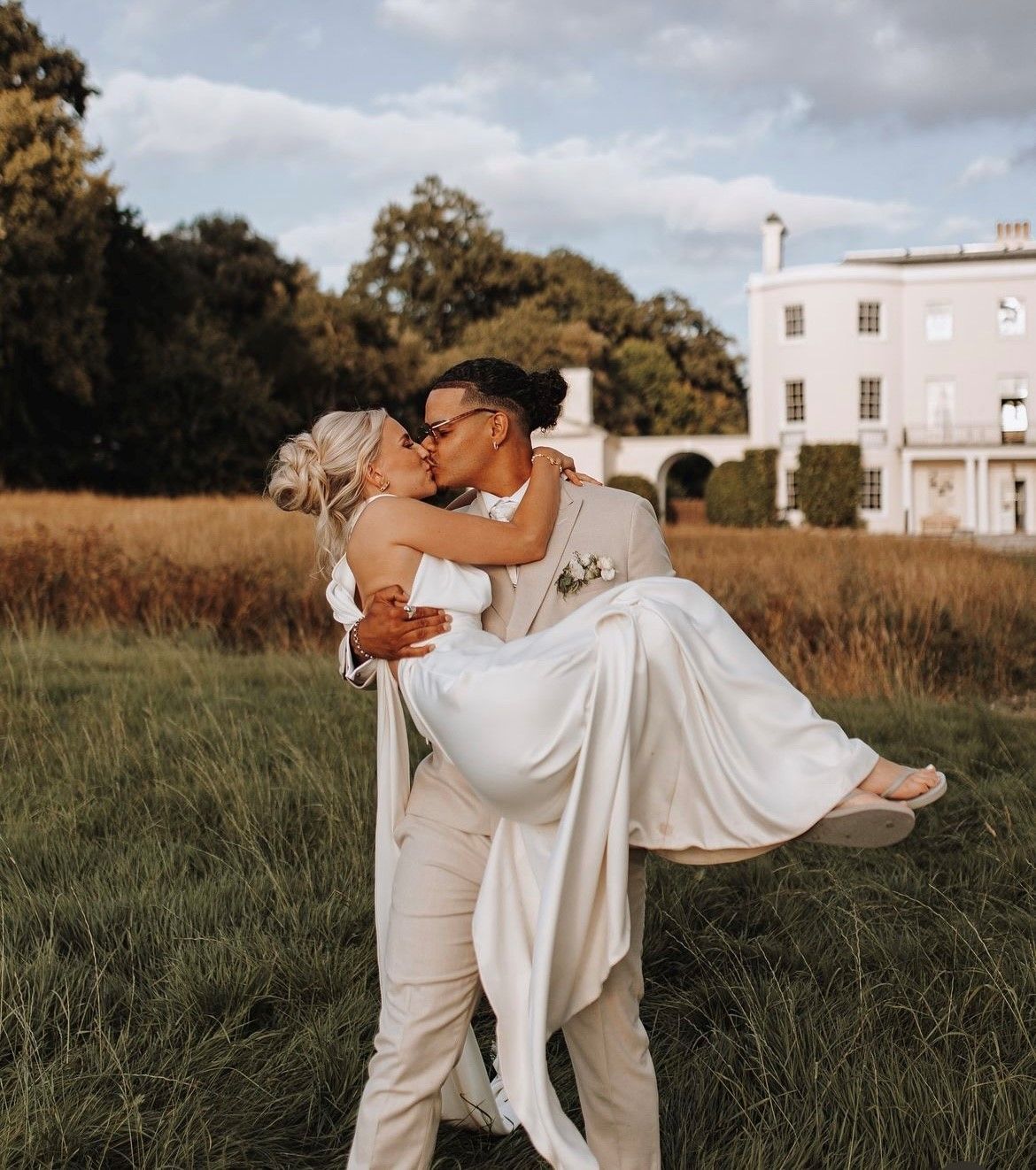 a black and white photo of a bride and groom walking in a field .