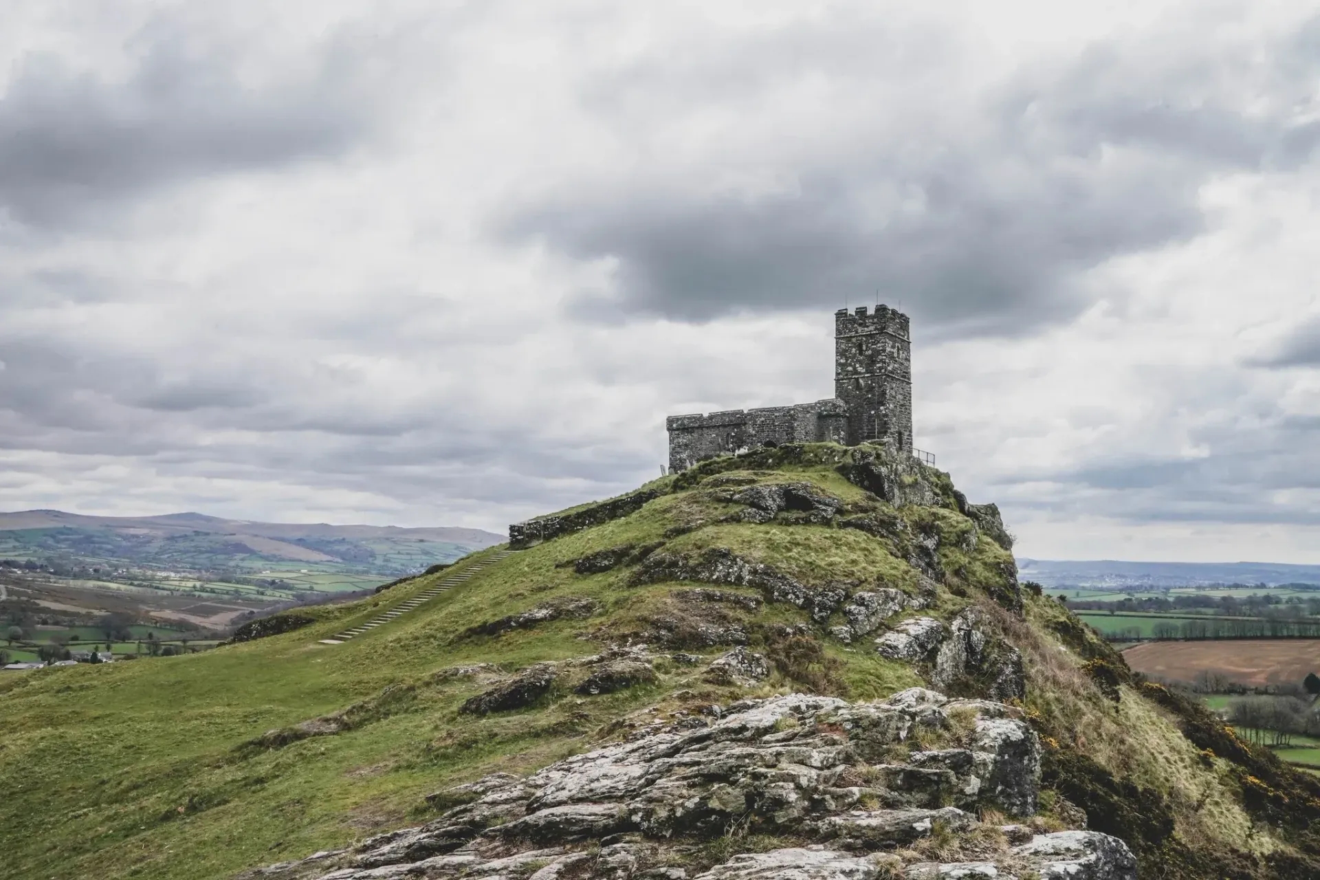 a castle on top of a hill with a cloudy sky in the background.