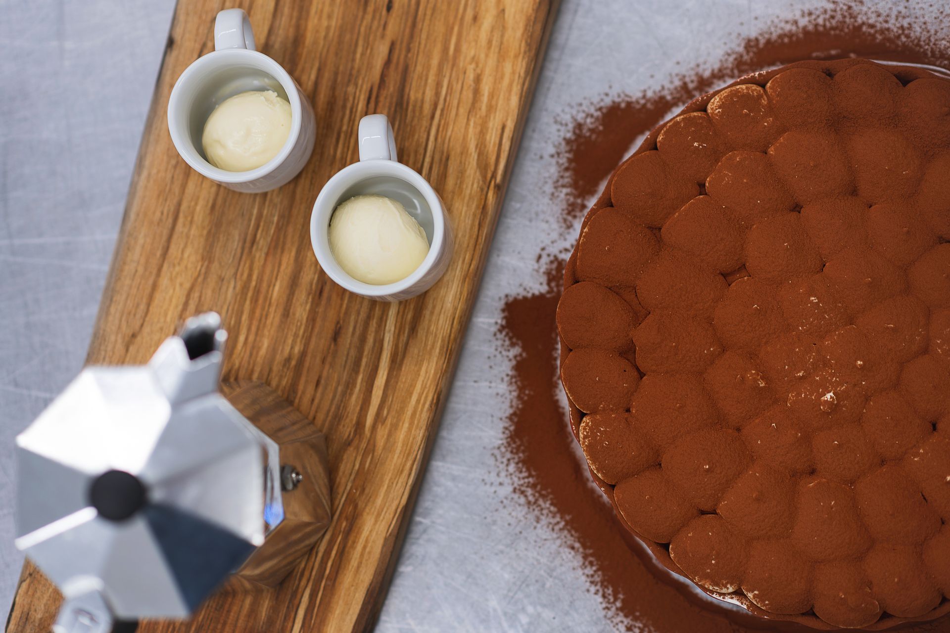 two cups of coffee and a cake on a wooden cutting board