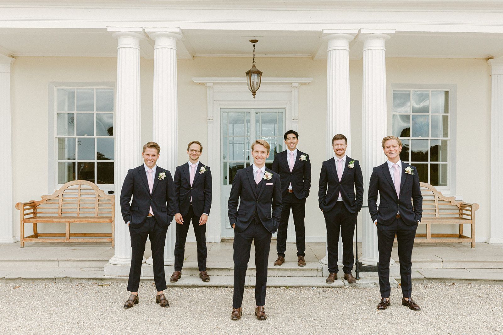 a group of men in suits are standing in front of a white building .