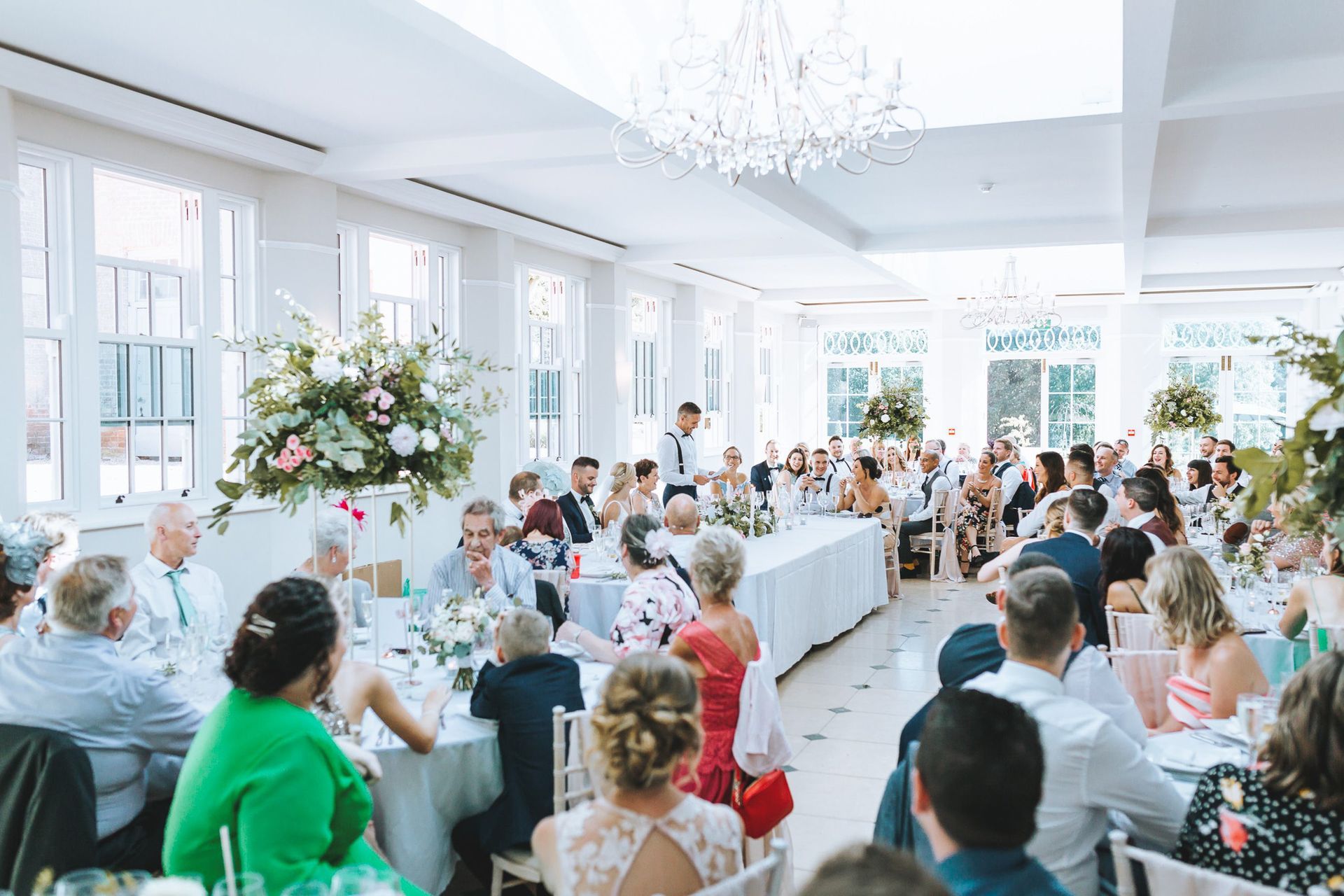 a large group of people are sitting at tables at a wedding reception .
