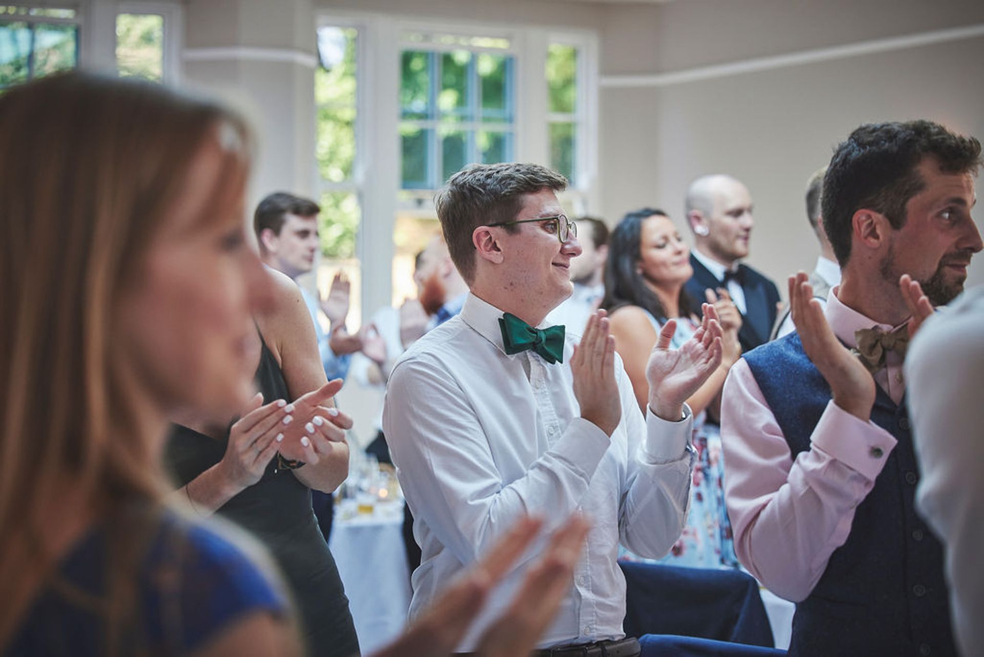 a group of people are clapping their hands at a wedding reception.