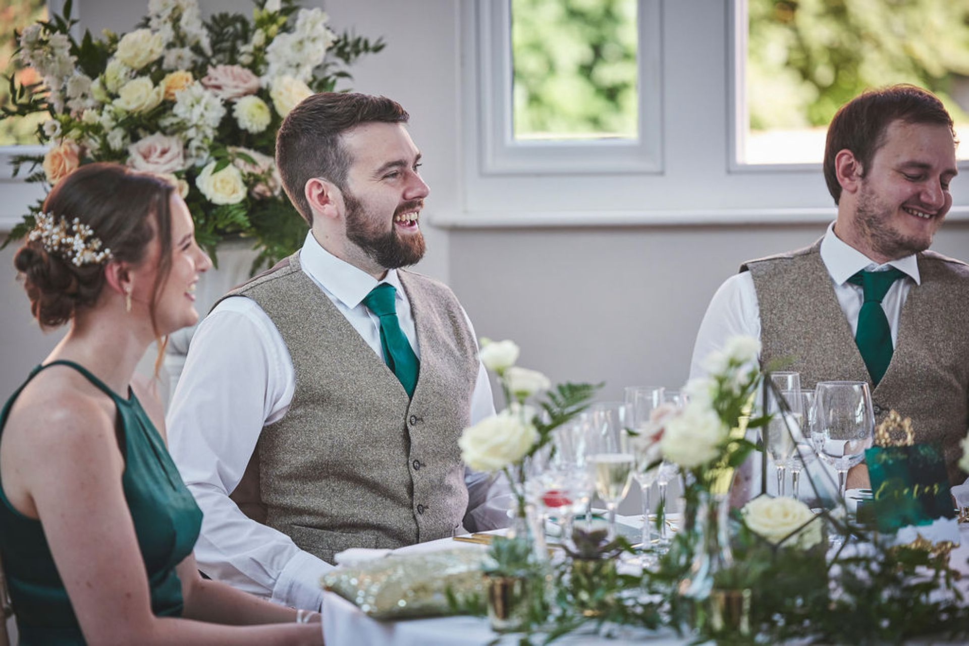 a group of people are sitting at a table at a wedding reception.