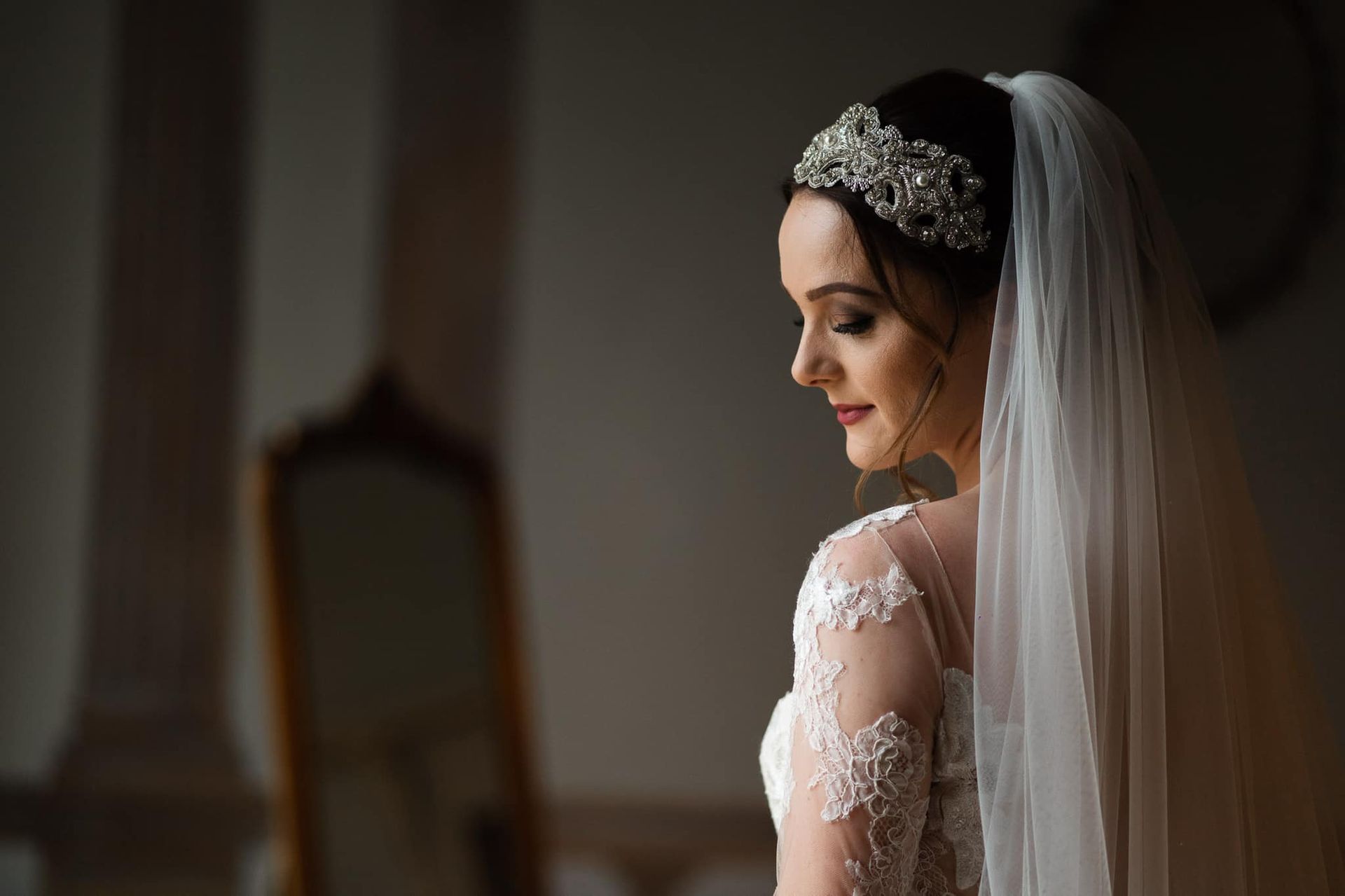 a bride in a wedding dress and veil is sitting in front of a mirror .