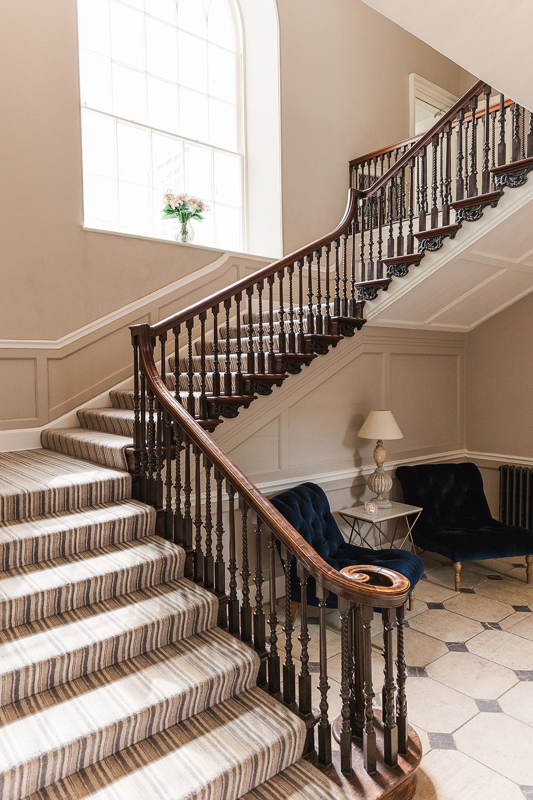 a large staircase in a house with a wooden railing and a striped carpet .