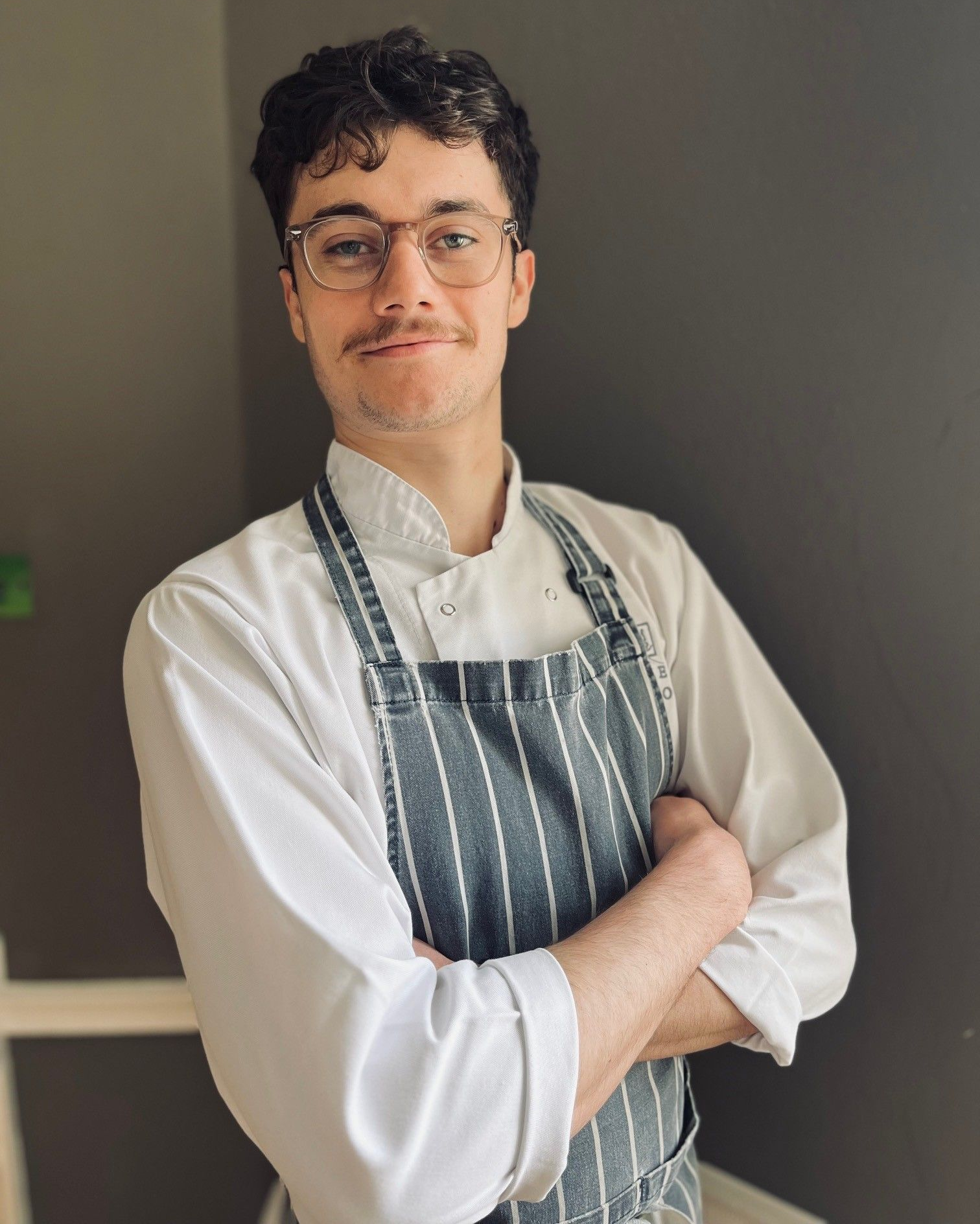 a young man in an apron is cooking on a stove .