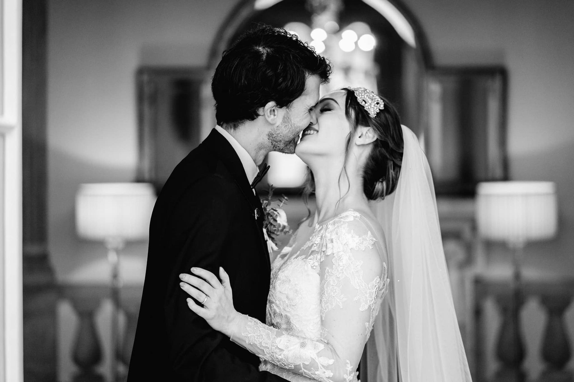 a bride and groom are kissing in a black and white photo .